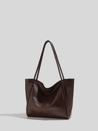 Brown leather tote bag on a light gray background showing texture in light
