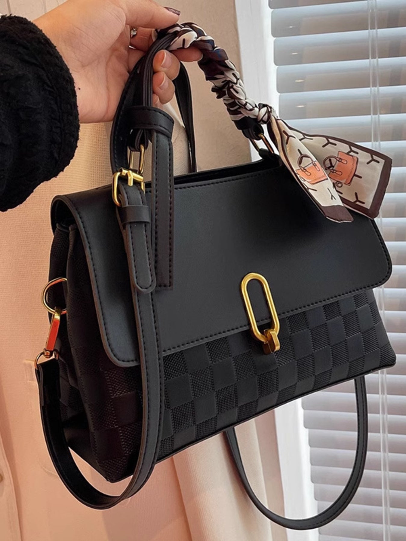 embossed crossbody bag held in hand front view