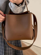 PU leather bucket crossbody bag hung from wrist, closer, shows size and detail